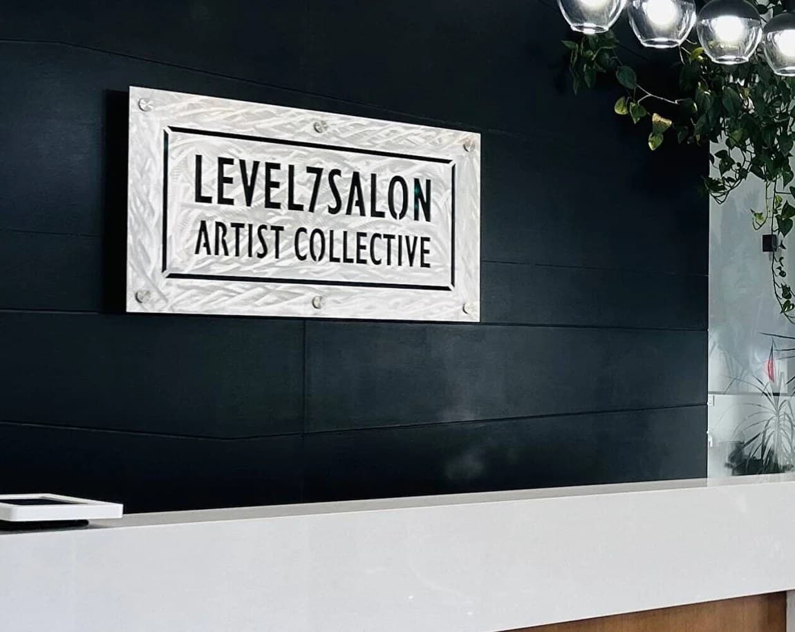 The Level 7 salon reception in Calgary, its Level7Salon Artist Collective sign on a dark wall above a white desk