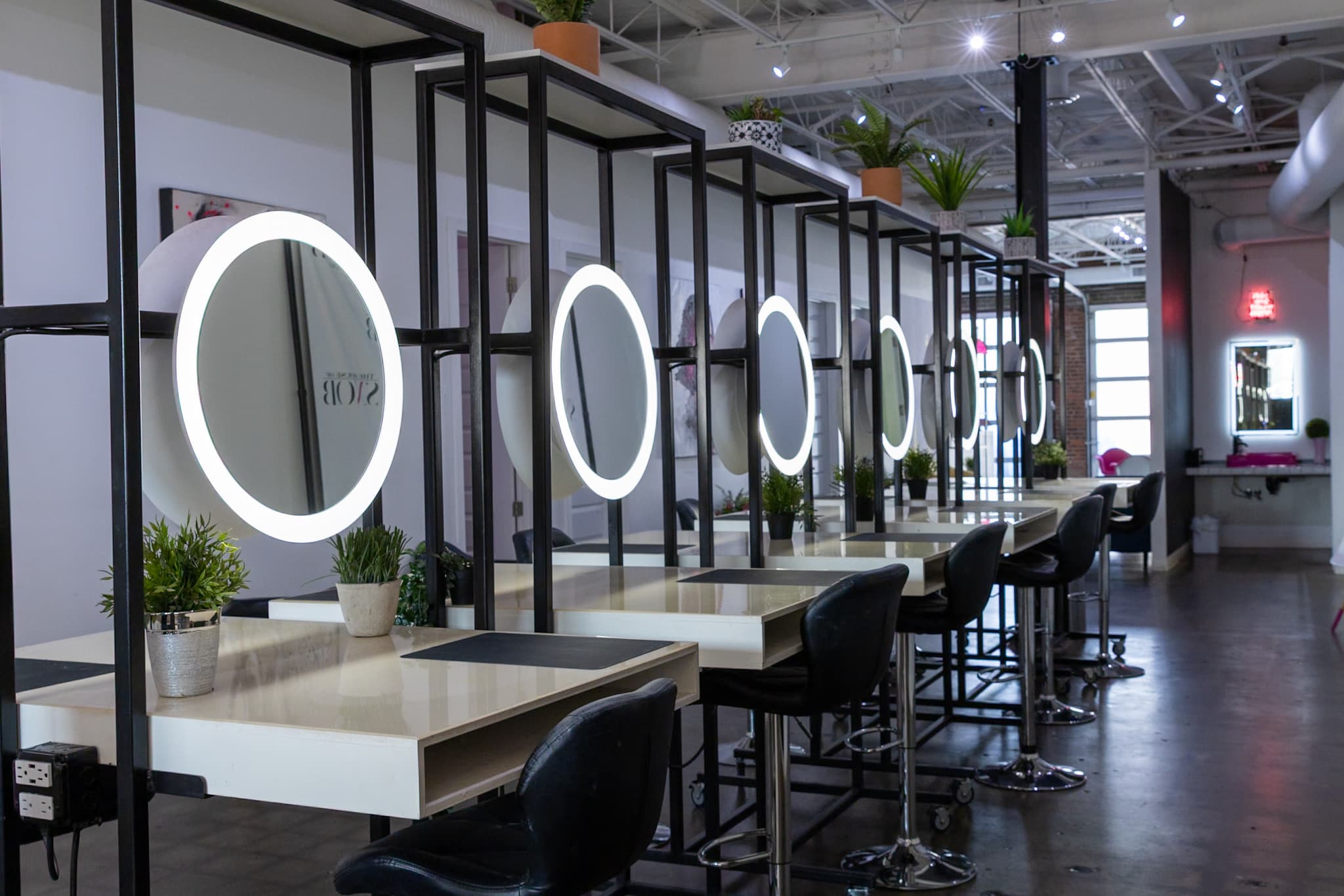Makeup stations with round lit mirrors on black steel frames at House of Snob in Edmonton